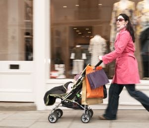 mother walking baby in stroller on sidewalk