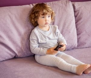 Toddler holding tv remote - best toddler shows on Netflix.