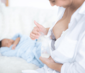 Mom sitting next to baby and using a breast pump. This article discusses the best sample pumping schedules.