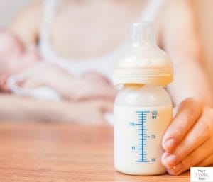 Mom holding baby and baby bottle on table. This post is all about nursing and pumping at the same time.
