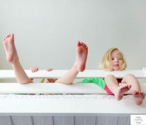 Two kids hanging out in bed. This article discusses tips for transitioning twins to toddler beds.