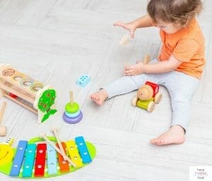 Toddler playing with toys on floor. This article discusses the top toddler must haves.