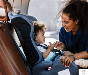 Mom putting baby in car seat. This article discusses the best narrow car seats on the market.