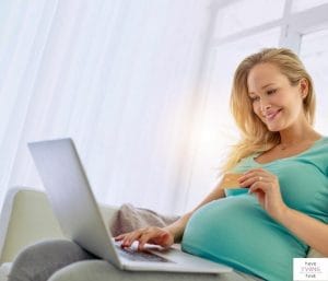 Pregnant mom to be looking at laptop. This article reviews how many items should be on a baby registry.