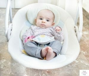 Baby hanging out in a baby swing. This article reviews the best baby swings that plug into a wall.