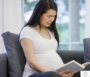 Pregnant mom reading a book. This articles discusses the best twin pregnancy books.
