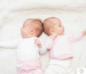 Newborn twin girls laying down. This articles answers the question: "when does raising twins get easier?"