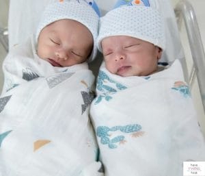 Newborn twins swaddled and sleeping. This article discusses the best newborn twins sleeping arrangements.