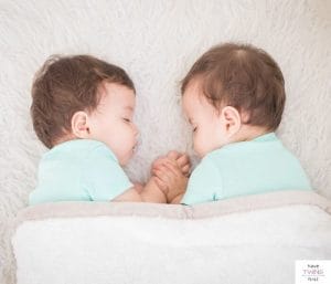 Twin babies sleeping. This article discusses how to solve twins sleeping problems.