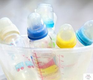 A bunch of baby bottles in a plastic container. This article discusses the question of how many baby bottles do I need.