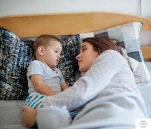 Mom and toddler in bed laying down and talking.