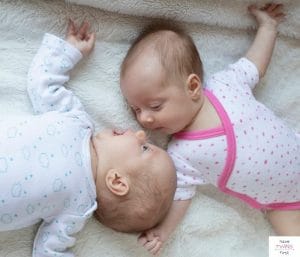Newborn twins laying next to each other and looking at each other. This article shares a list of twin baby must haves