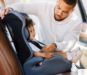 Dad putting child in front-facing car seat. This article discusses the best budget car seats.