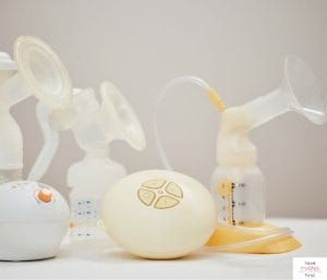 Various brands and types of breast pumps on a shelf. This article discusses needs for pumping at work supplies.