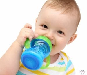 Toddler drinking milk from a sippy cup. This article discusses how to switch from formula to milk.