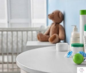 Baby's room with crib and two tables with a teddy bear on one of them. This article discusses the best budget nursery furniture.