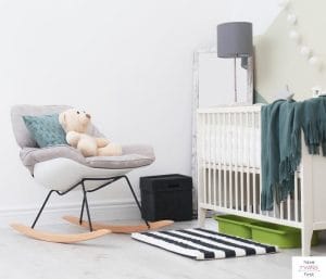 Baby's nursery with a crib, chair, lamp, and nightstand. This article discusses the best nursing chair for twins.