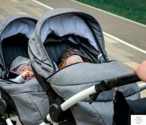 Infants being pushed in a double tandem stroller. This article discusses the best strollers for newborn twins.