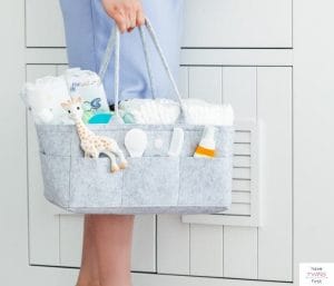 Woman standing and holding a diaper organizer. This article discusses what to put in a diaper caddy.