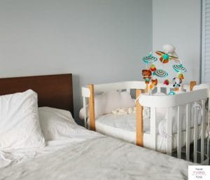 Baby bassinet next to a bed. This article discusses the best bassinets for tall beds.