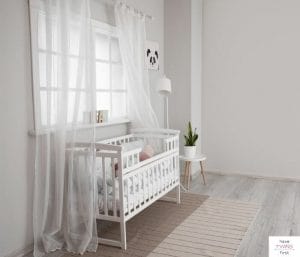 Baby's crib in front of a window in the nursery.