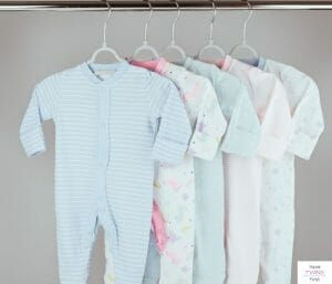Baby clothes hanging in a closet. This article asks how long do babies wear newborn clothes.