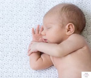 Newborn baby sleeping on white blanket. This article asks how long is the newborn stage.