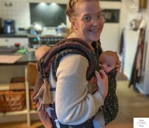 Twin mom using baby carriers to hold two babies simultaneously. This article discusses how to carry twins at the same time.