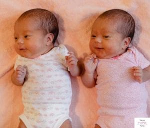 Newborn twins lying down on a peach colored blanket. This article discusses what it's like to have twins born at 35 weeks.