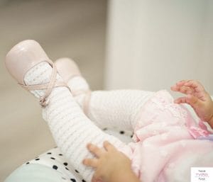 Baby girl's legs with tights and baby shoes on. This article discusses the baby items you can live without.