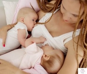 Mom breastfeeding twin babies simultaneously. This article discusses the best breastfeeding twins schedule.
