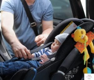 Parent buckling newborn baby into a rear facing car seat. This article discusses the best car seats for twins.
