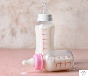 Two baby bottles with pink writing on a counter. This article discusses how to choose baby bottles.